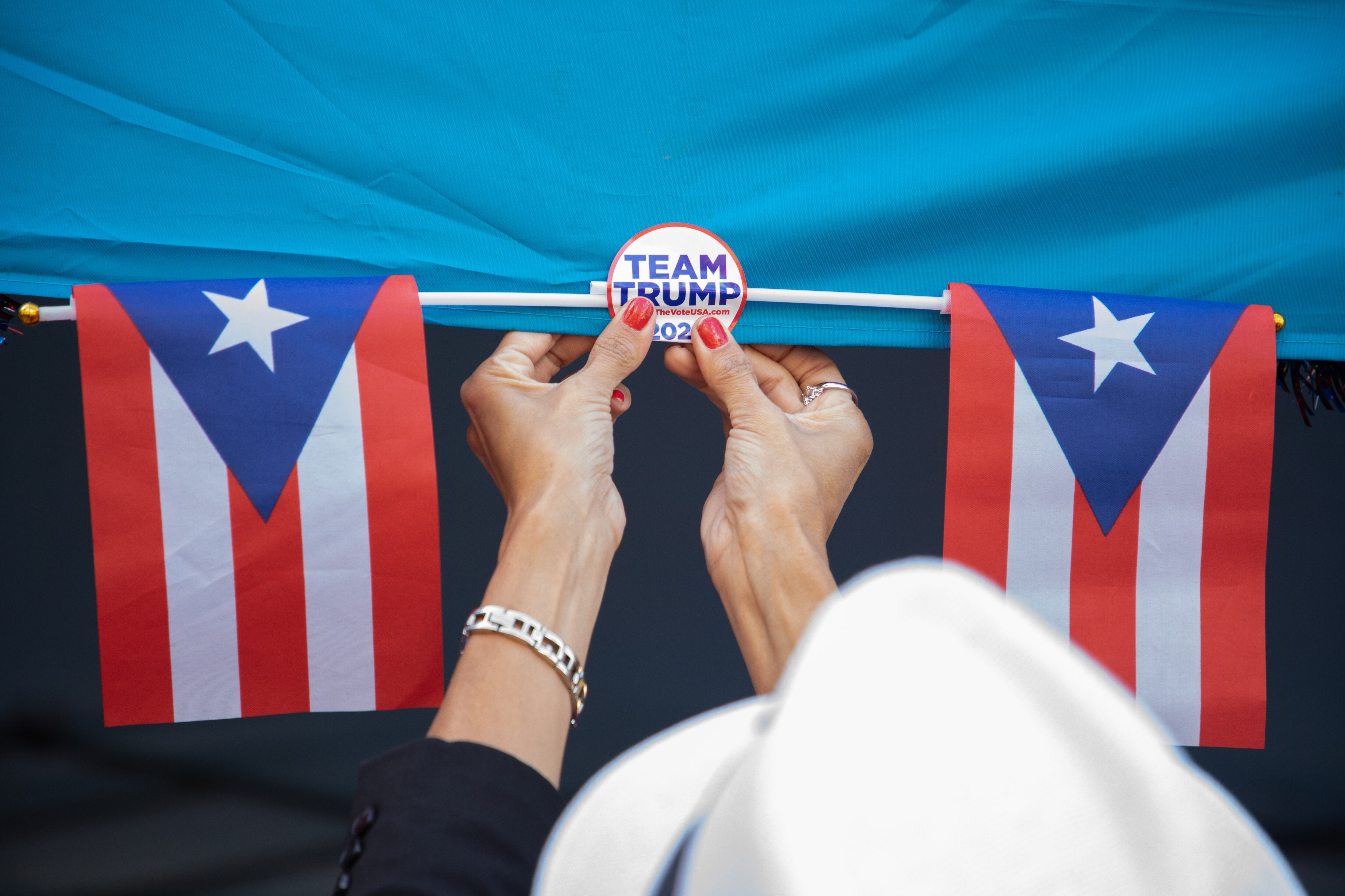 Um voluntário da campanha de Trump coloca um distintivo do candidato republicano próximo às bandeiras de Porto Rico em 8 de setembro em Reading, Pensilvânia.