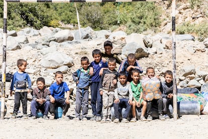 Un grupo de niños posa en el campo de fútbol de tierra del valle. Los mayores conducen los burros y mulas llevando la ayuda que ha llegado entre las rocas caídas sobre la pista.