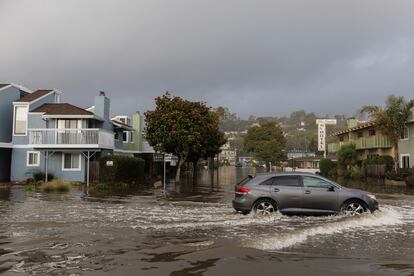 Un vehículo circula por una avenida inundada en la ciudad de Aptos, en el norte de California.