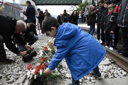 A boy lays flowers on the tracks at the railway station of Rapsani, north Greece, on March 5, 2023, during a commemorative gathering for the victims of a deadly train crash.