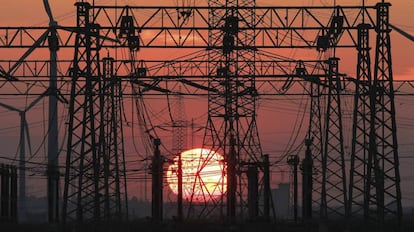 Puesta de sol junto a un tendido el&eacute;ctrico y unos molinos de viento (izq).