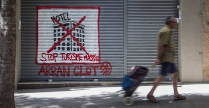 Un hombre delante de una pintada contra el turismo masivo en Barcelona.