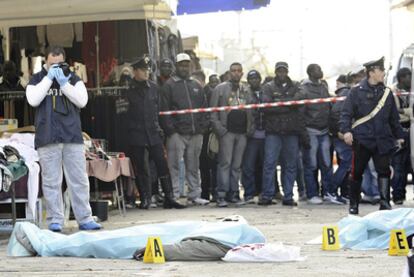 La policía científica toma fotos del los cadáveres de dos senegaleses asesinados en Florencia en presencia de varios compatriotas de las víctimas.