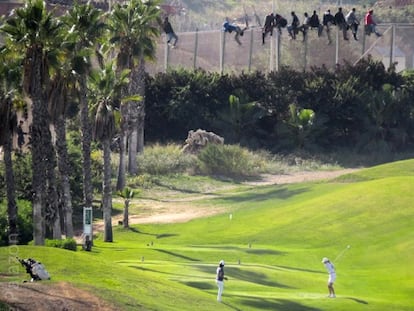 Un grupo de inmigrantes permanecen subidos a la valla de Melilla, frente al campo de golf de la ciudad.