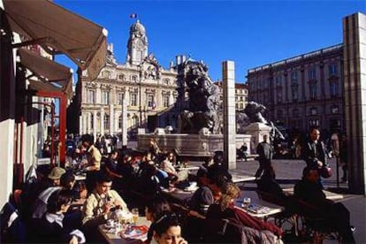 Animadas terrazas en la plaza de Terraux de Lyón, donde la monumental fuente de Bartholdi convive con las columnas modernas del artista Daniel Buren.