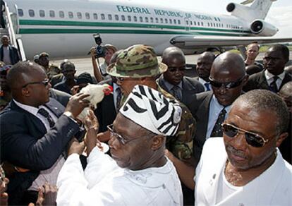 El presidente de Liberia, Taylor (derecha), y su homólogo nigeriano, Obasanjo (centro), en el aeropuerto de Monrovia.