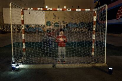 Un niño espera su turno para realizar un ejercicio ya entrada la noche. Tan solo unas cuantas lámparas de camping iluminan las porterías para que el juego no pare.