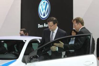 El presidente del Gobierno, Mariano Rajoy,  acompañado por  Patrick Danau,d., director general de Volkswagen Navarra,  entra en un modelo de esa marca durante su visita al Salón del Automóvil.