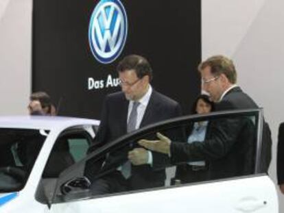 El presidente del Gobierno, Mariano Rajoy, acompañado por Patrick Danau,d., director general de Volkswagen Navarra, entra en un modelo de esa marca durante su visita al Salón del Automóvil.