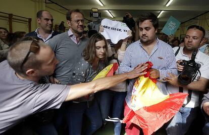 Una persona intenta prendre una bandera espanyola a un membre de VOX al col·legi electoral on ha anat a votar Artur Mas.