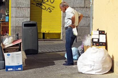 Reguero de bolsas y cajas alrededor de unas papeleras en el barrio de Lavapiés.