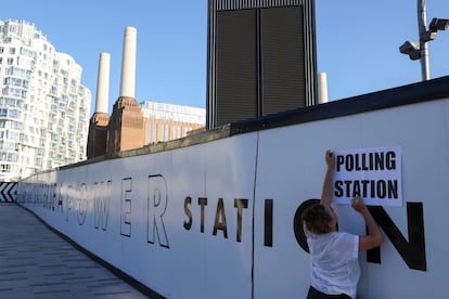 A woman puts up a sign advertising a polling station in London on Thursday. 