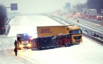 Un camión de bomberos permanece junto a dos camiones, uno de ellos volcado, después de que sufrieran un accidente en la A5 hoy debido a la nieve en Weitestadt en Alemania.