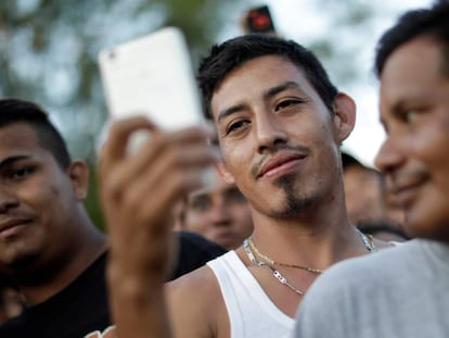 Un migrante de la caravana que viaja desde Centroamérica hacia Estados Unidos usa su teléfono móvil en un campamento improvisado.