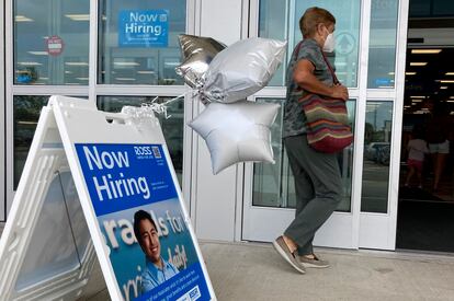 Una mujer junto a un letrero de contratación antes de ingresar a una tienda minorista en Morton Grove, Illinois.