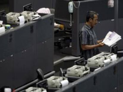 Un agente de bolsa indonesio lee el periódico durante una pausa en la actividad de la bolsa en Yakarta (Indonesia).