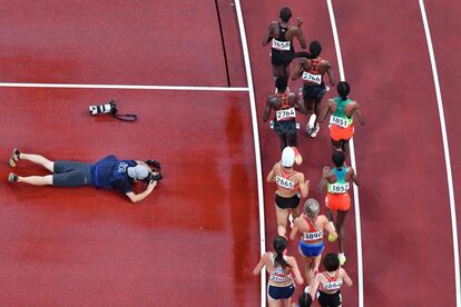 Un fotógrafo toma imágenes durante la prueba eliminatoria de los 5.000m femeninos.