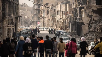 Um grupo de pessoas caminha por uma rua de Homs.