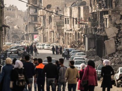 Um grupo de pessoas caminha por uma rua de Homs.