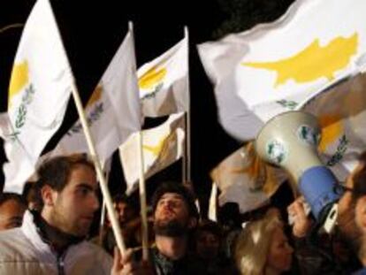 Varios asistentes muestran pancartas durante una manifestaci&oacute;n frente al Parlamento de Chipre.