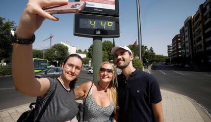 Unos turistas se fotografían con un termómetro del centro de Córdoba.