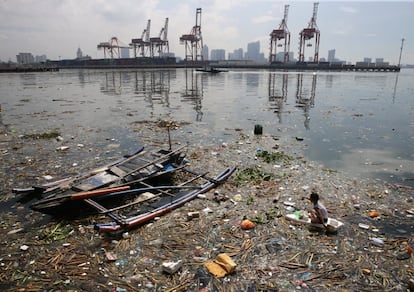 Un ni?o recoge botellas de plstico a bordo de una peque?a balsa improvisada hecha de tablas desechadas y espuma de poliestireno para recoger botellas de plstico reciclables de entre la basura, en Baseco, Manila (Filipinas).