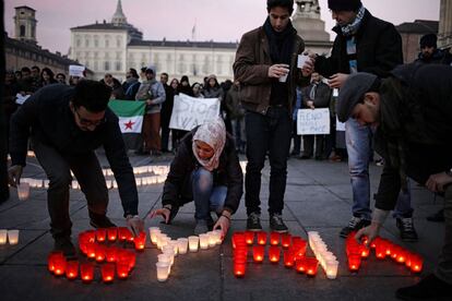Varias personas escriben con velas las palabras "Save Syria" ('Salvar Siria'), durante una manifestación en apoyo de la gente de la ciudad de Alepo, en la Piazza Castello de Turín (Italia), el 18 de diciembre de 2016.