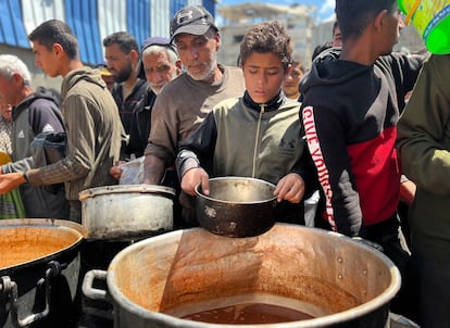 Palestinos recogen comida distribuida por organizaciones caritativas, en el campamento de Nuseirat, en el centro de Gaza, este martes.