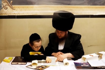 Un hombre y un niño judíos ultraortodoxos participan en la lectura del Libro de Ester en la fiesta de Purim, una celebración de la salvación de los judíos del genocidio en la antigua Persia, en una sinagoga en Bnei Brak, cerca de Tel Aviv, 
