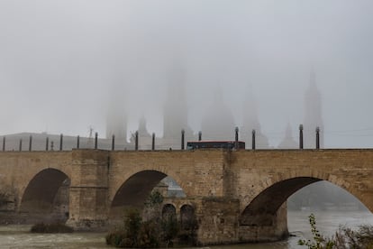 La catedral de Zaragoza, oculta por la niebla este jueves desde el puente de piedra.