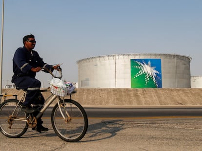 Un empleado pasa en bicicleta cerca de un tanque de petróleo de Aramco, la petrolera estatal saudí.