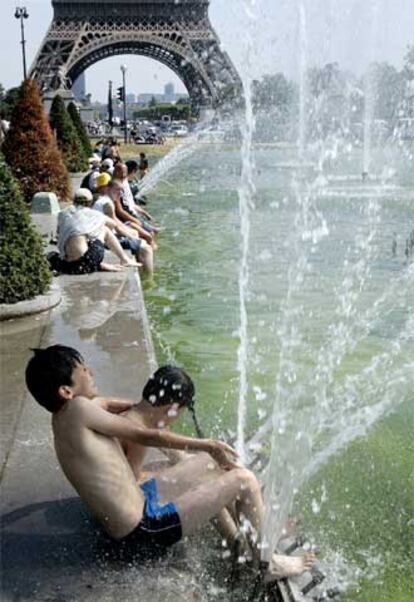 Un grupo de niños se refresca en un estanque junto a la torre Eiffel.