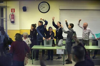 Pessoas protegem a urna da polícia, com os punhos para o alto, no interior de uma escola de Barcelona.