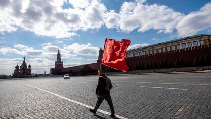 Una persona cruza la plaza Roja de Moscú sujetando una bandera de la Unión Soviética.