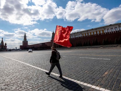 Una persona cruza la plaza Roja de Moscú sujetando una bandera de la Unión Soviética.