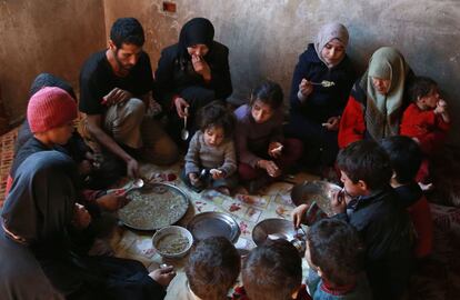 Una familia siria se reúne para comer un plato de maíz y repollo en Saqba, cerca de Damasco (Siria).