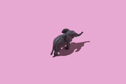 Una miniatura de un elefante de plástico sobre un fondo rosa.