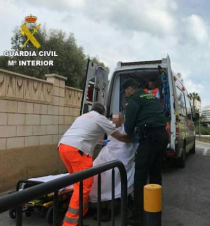 Un sanitario y un agente de la Guardia Civil trasladan el cad&aacute;ver de la mujer.