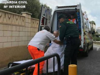 Un sanitario y un agente de la Guardia Civil trasladan el cad&aacute;ver de la mujer.