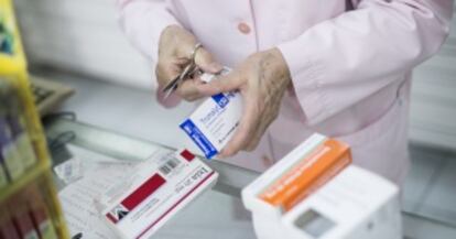 Una farmacéutica sirve medicamentos a unos clientes en una botica de Barcelona.