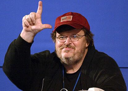 El cineasta Michael Moore responde desde la tribuna de prensa con el gesto de "perdedores" a las críticas vertidas por McCain contra él en su discurso.