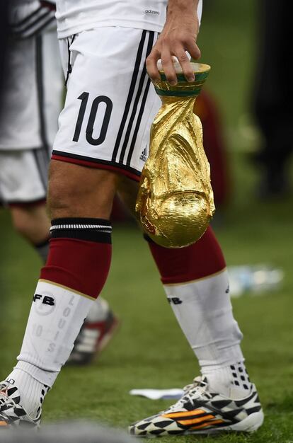 Lukas Podolski sostiene el trofeo del Mundial tras el partido
