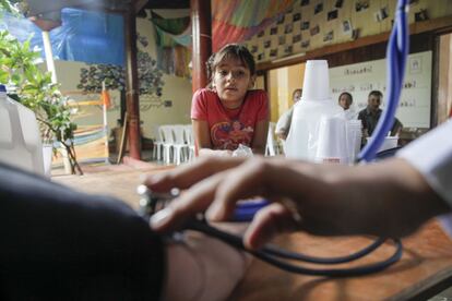 Una niña observa como le realizan pruebas a un visitante a la feria de la diabetes.