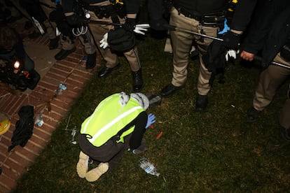 Un manifestante pro-Palestina reza a los pies de elementos de la Policía de California.