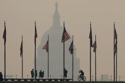 Los turistas caminan alrededor de la base del Monumento a Washington, mientras el humo de los incendios forestales arroja una neblina sobre el Capitolio de los Estados Unidos en Washington.