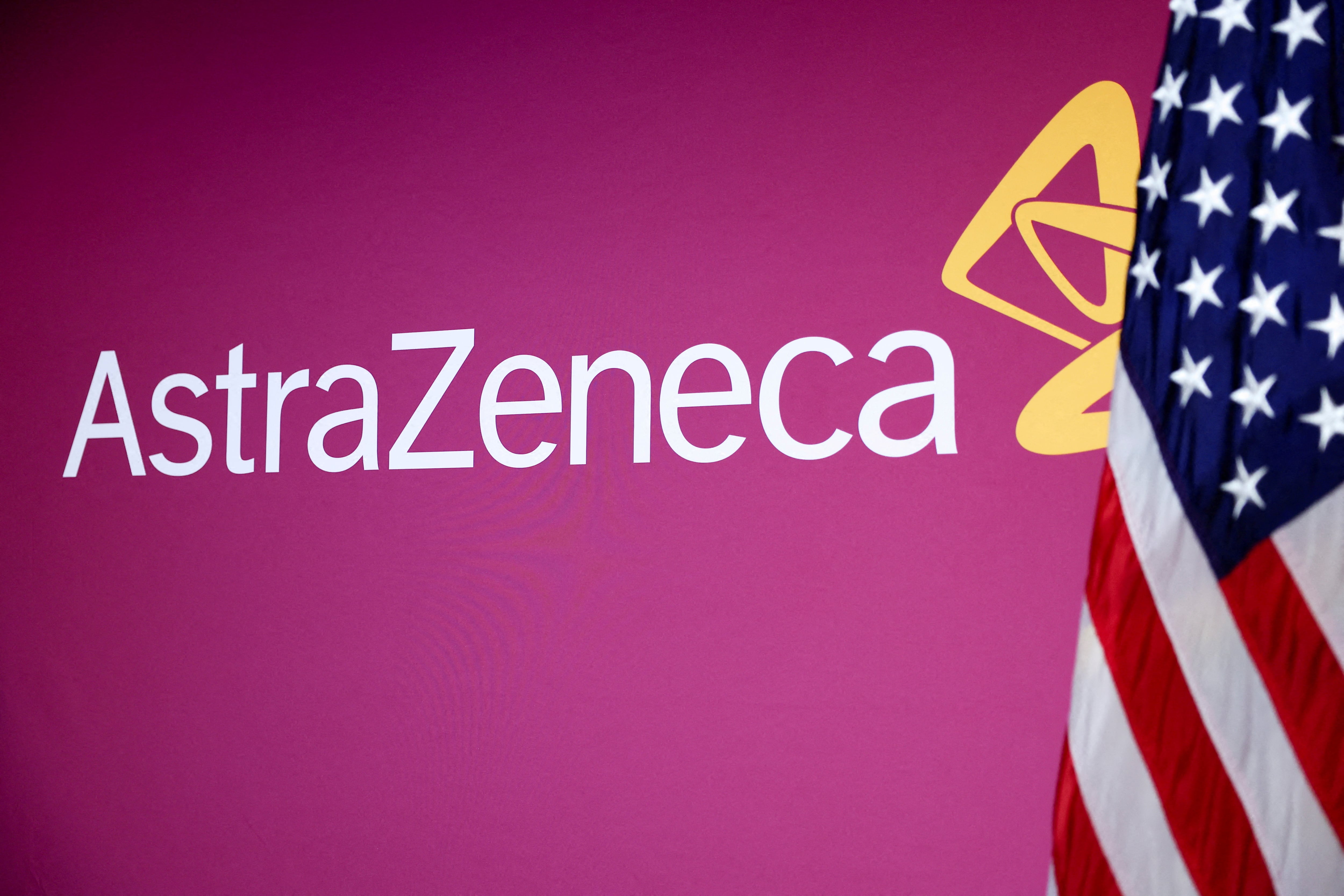 Imagotipo de AstraZeneca junto a una bandera de Estados Unidos.
