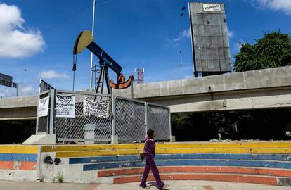 Una mujer camina frente a una bomba de extracción en la Universidad de Caracas.