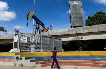 Una mujer camina frente a una bomba de extracci&oacute;n en la Universidad de Caracas. 