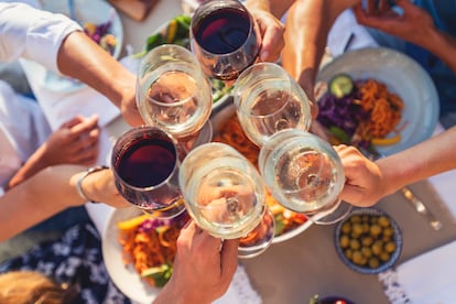 Varias personas brindan con copas de vino.