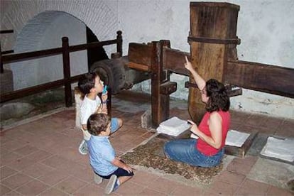 La guía del museo de Capellades, Luisa Huerta, plancha papel para mostrar el funcionamiento del mazo satinador.